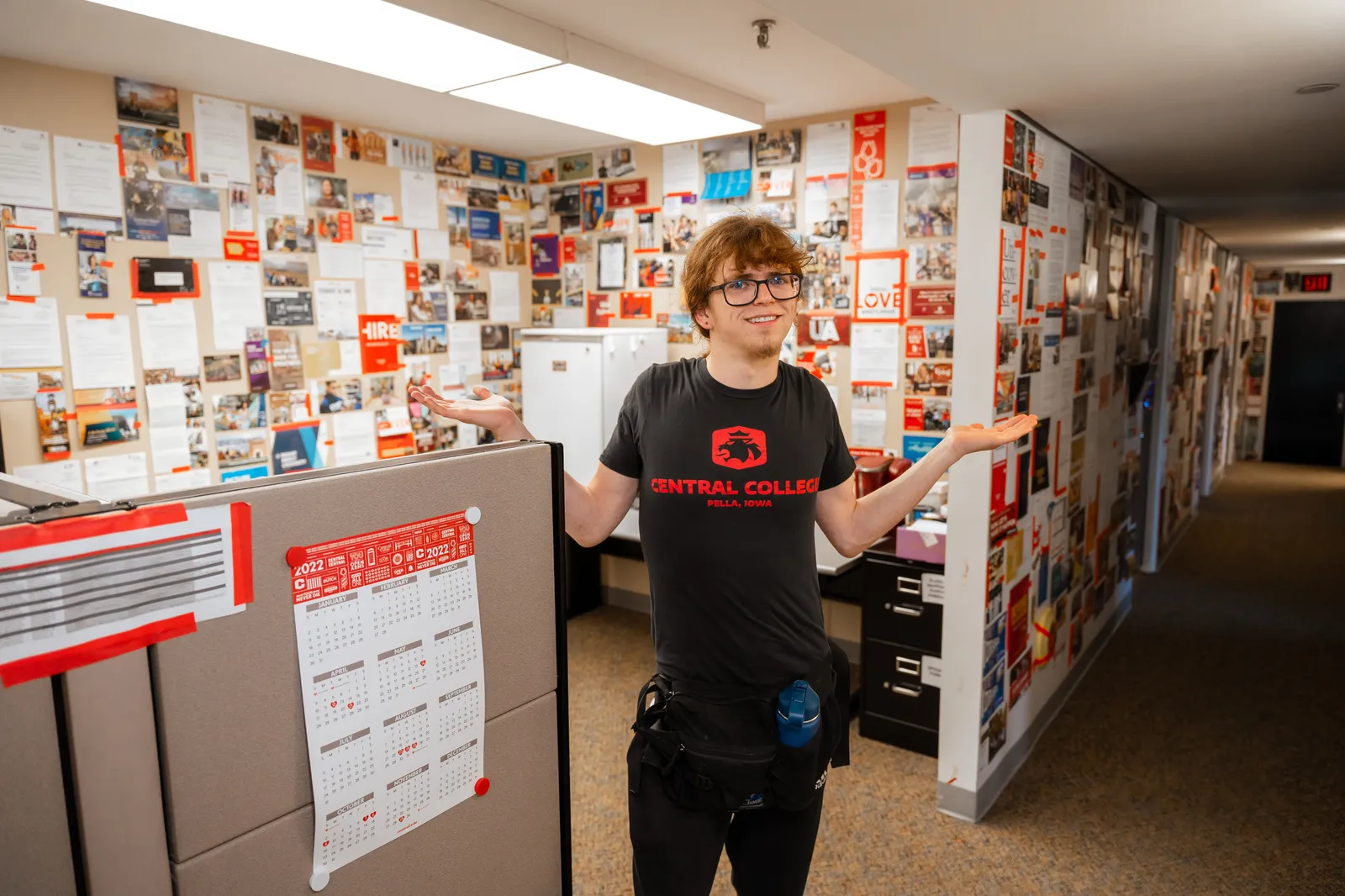 Someone stands in front of college admissions materials taped to the wall.