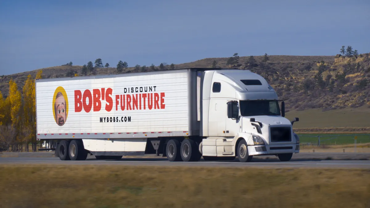 A Bob's Discount Furniture truck drives on a road.