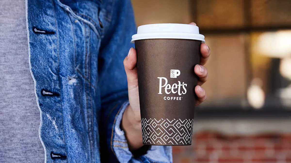 An image of a hand holding a Peet's Coffee cup