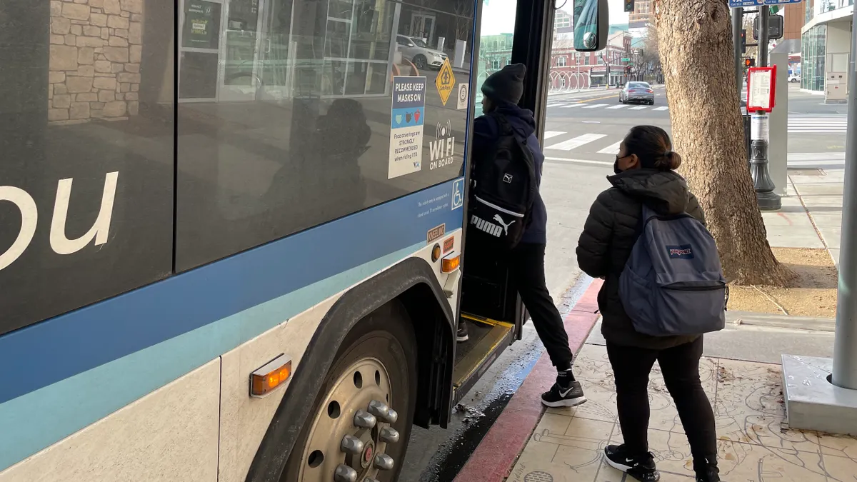 People entering a bus stopped at a curb.