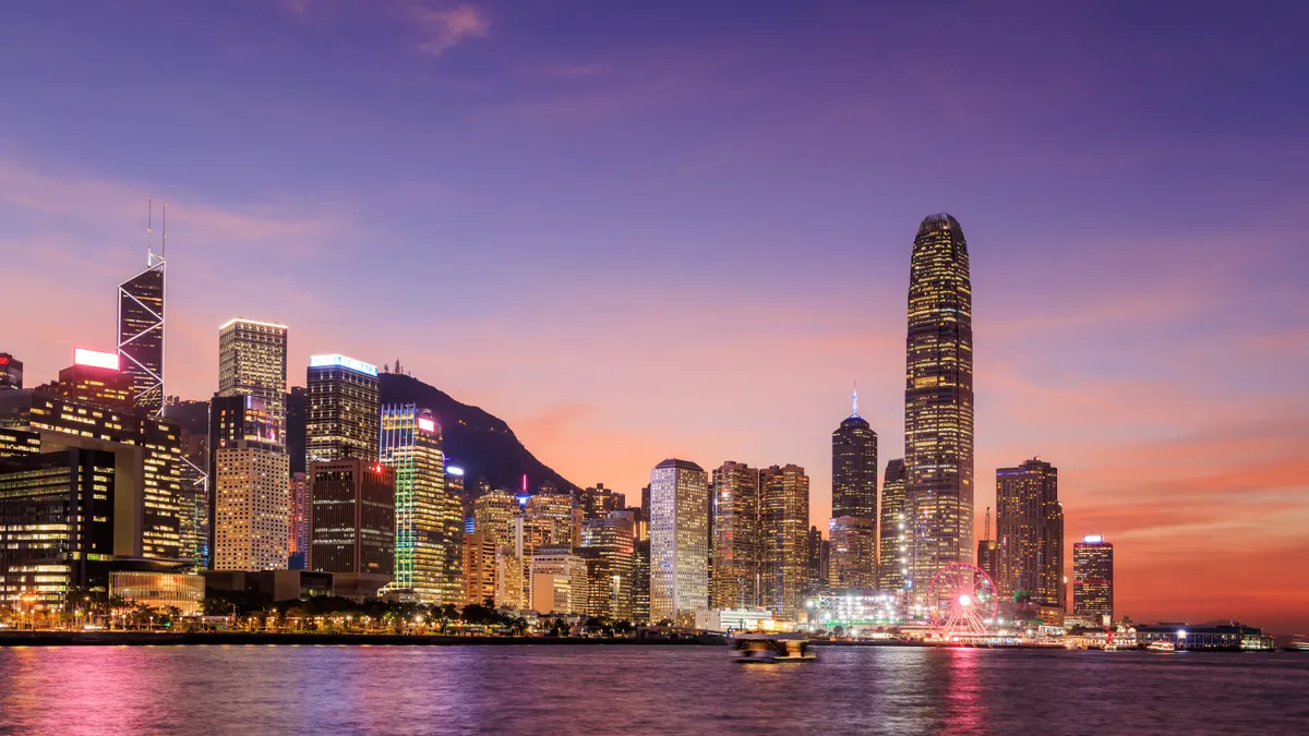 A photo at dusk of a city across the water that is brightly lit up with skyscrapers.