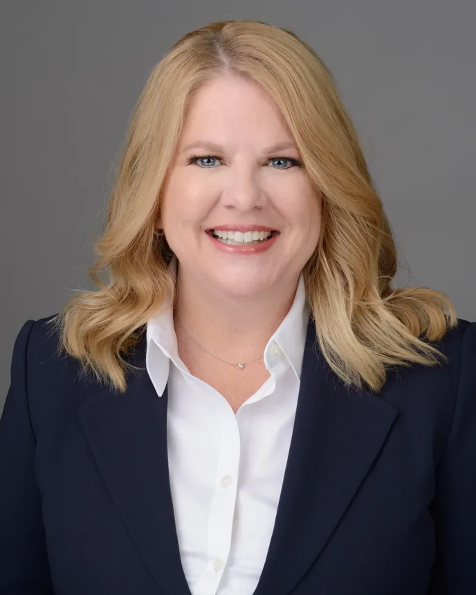 Headshot of a blond woman in a blue suit.