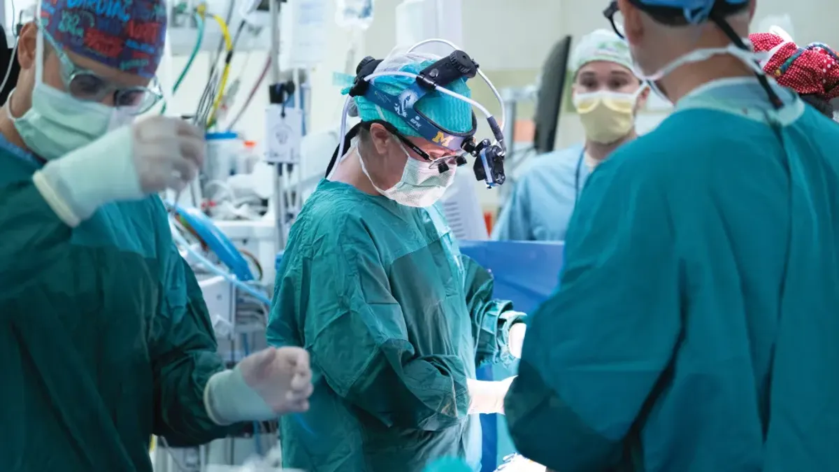 Surgeons wearing blue gowns perform an operation.