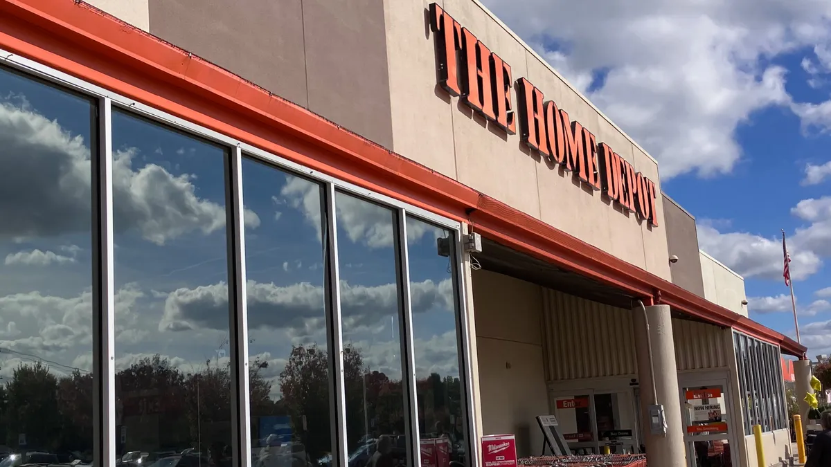 A Home Depot storefront with a blue sky and lawnmowers in front