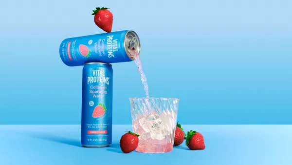 A sparkling water is poured into a glass over ice.