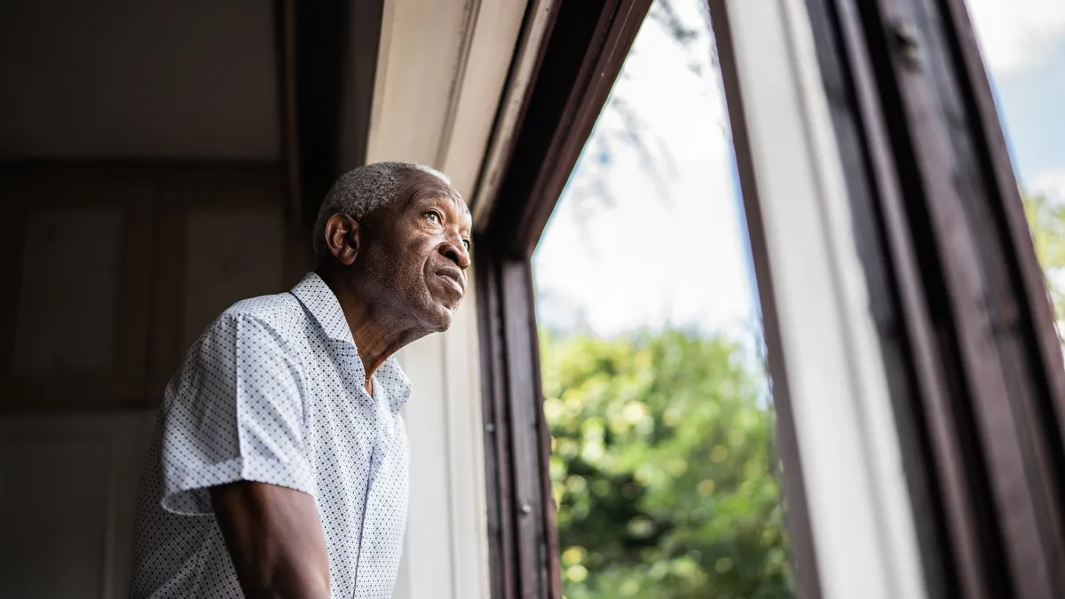 A person stands by a window and looks outside.