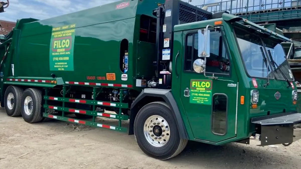 Green waste collection truck sitting in parking lot