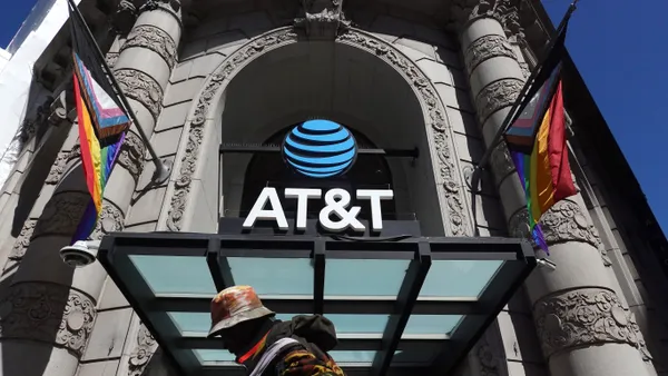 A pedestrian walks by a sign posted in front of an AT&T store.