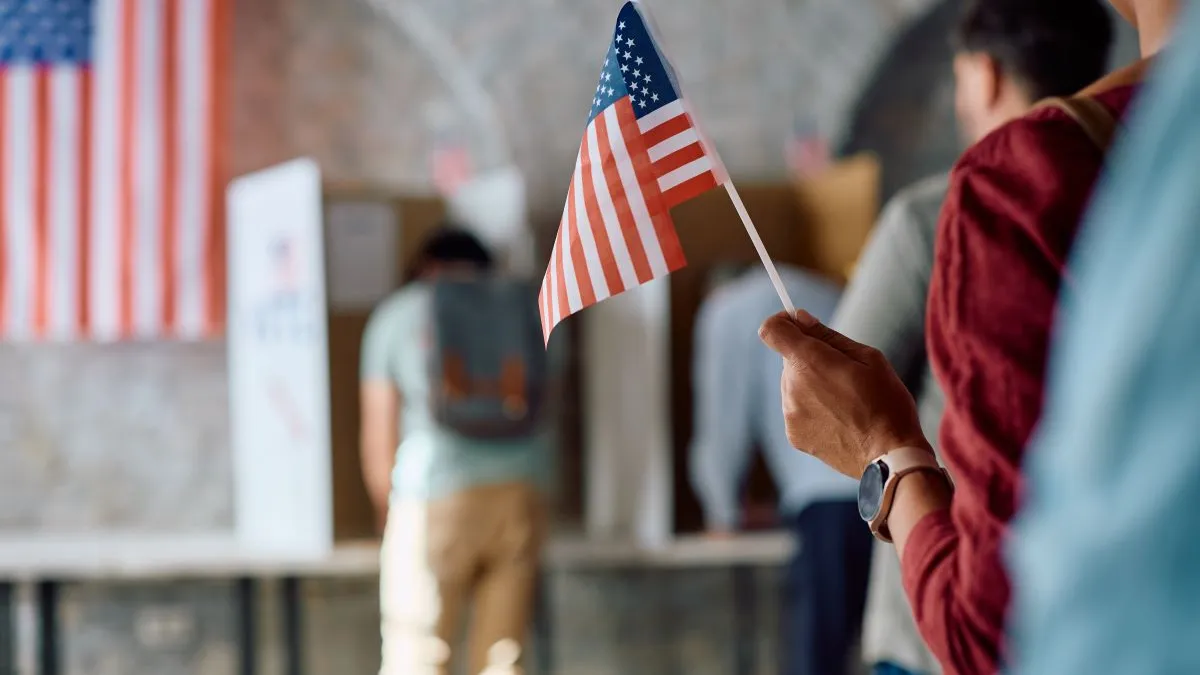 Close up of African American voter with national flag in waiting line during US elections.