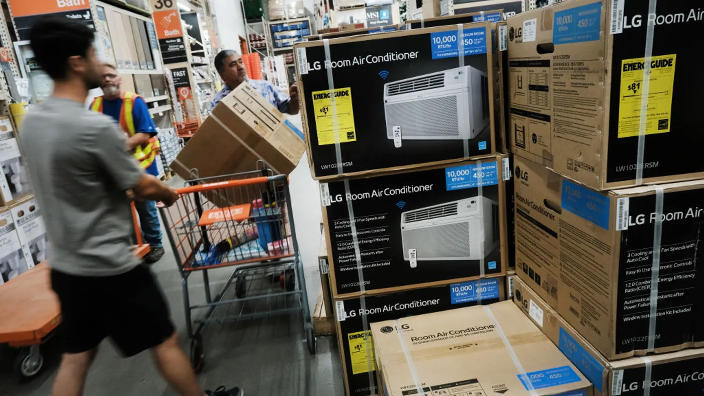 Two men look at a stack of air conditioners in boxes.