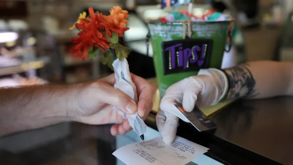 Hand of consumer and merchant hovering over receipt.