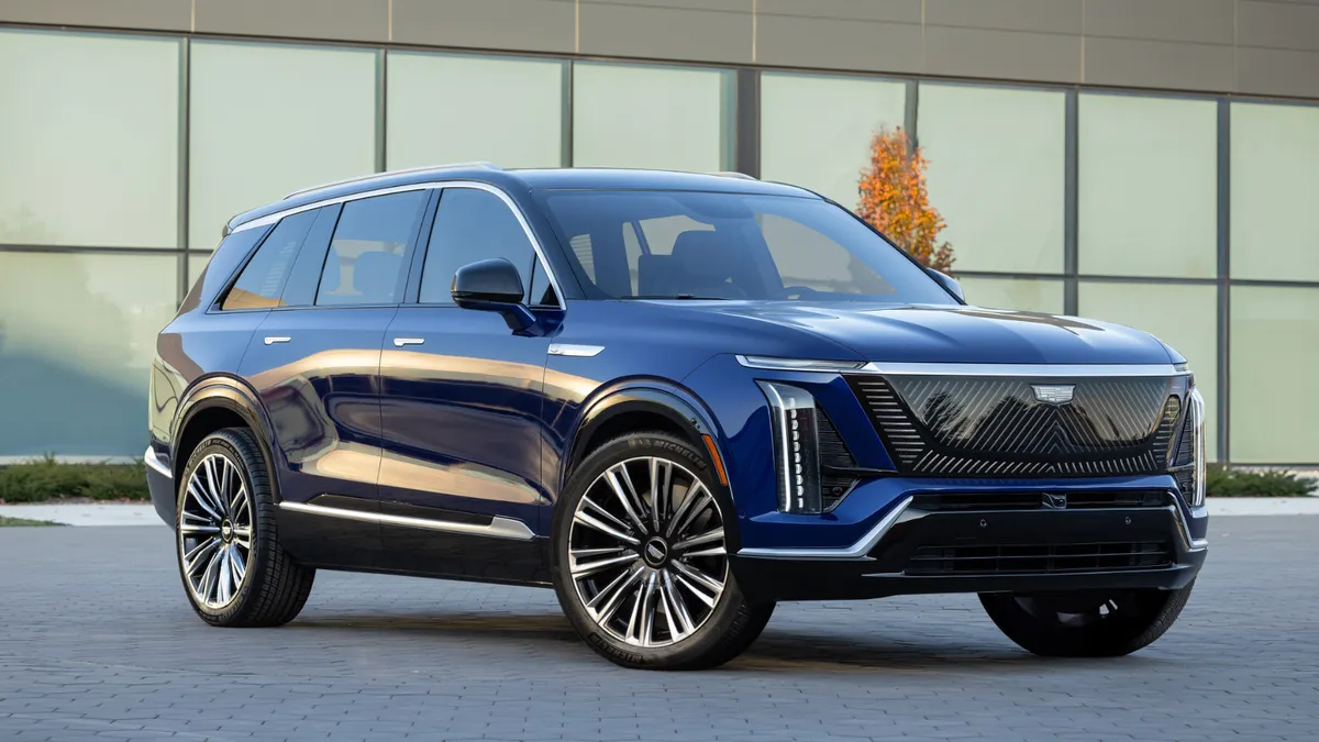 A front 3/4 view of a 2026 Cadillac VISTIQ in Opulent Blue Metallic parked in front of a building.
