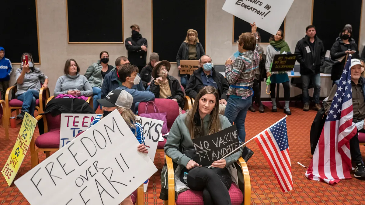 People hold signs reading "Freedom over fear" and "Parents rights in education."