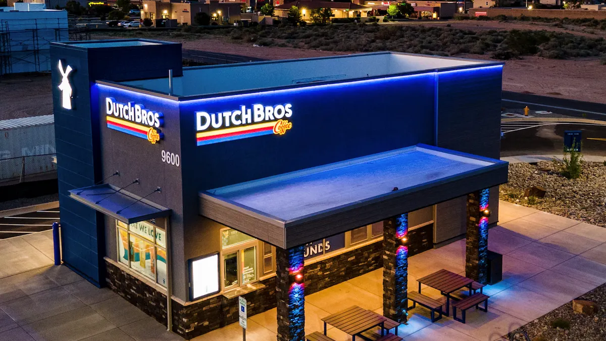 An evening image of a blue building with Dutch Bros signage.
