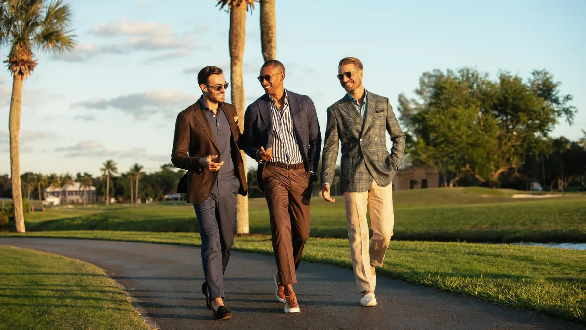 Three people walking down an asphalt path in formalwear.