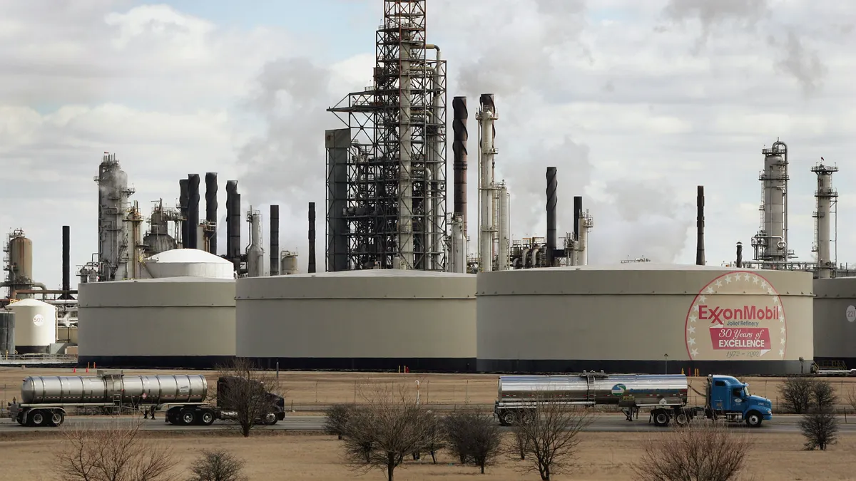 Tanker trucks drive past an ExxonMobil oil refinery.