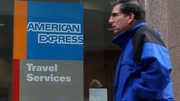 A pedestrian walks by an American Express Travel Services office.