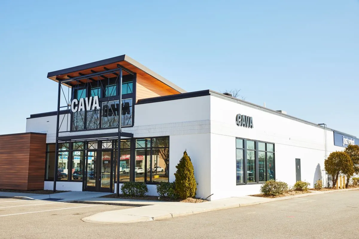 A white building with windows on the front with a large sign that says Cava