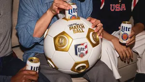 Three people sit on a sofa, heads not visible. All three hold Miller Lite's, with the person in the center holding the matchball.