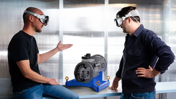 two people wearing goggles standing next to a 3D printed equipment.