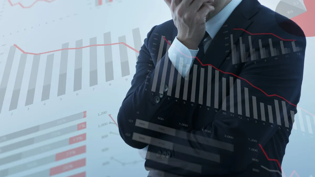 Businessperson feeling anxiety and stress amid graphics of declining graphs and charts.