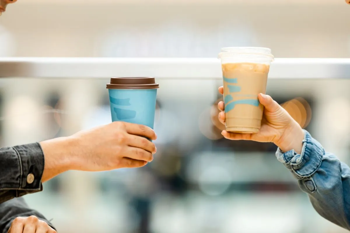 An image of two arms holding up Caribou Coffee drinks