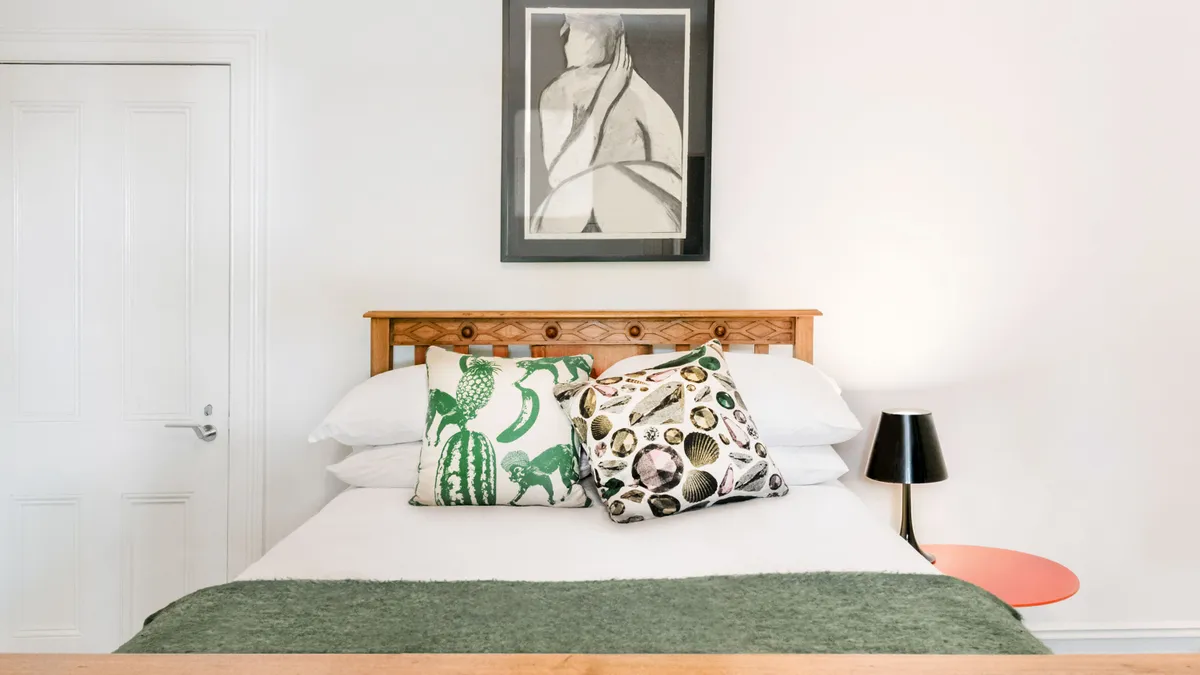 An Airbnb room rental featuring a bed with decorative pillows and artwork hanging above.