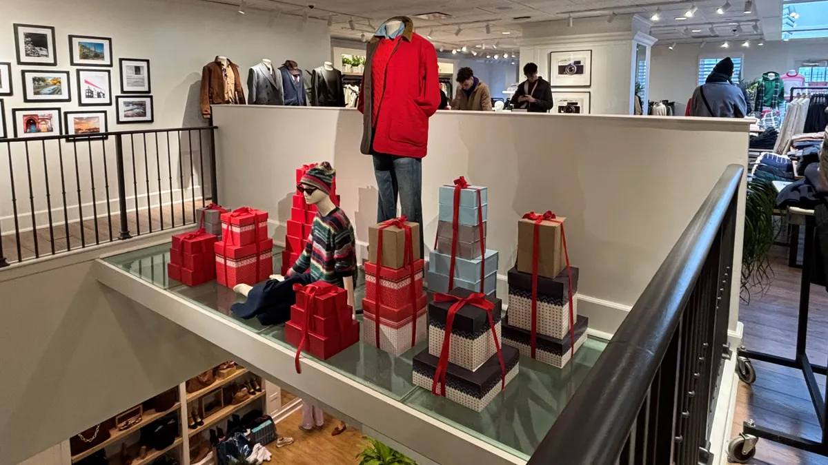 Interior J. Crew storefront with mannequins modelling red winter clothing next to holiday gifts