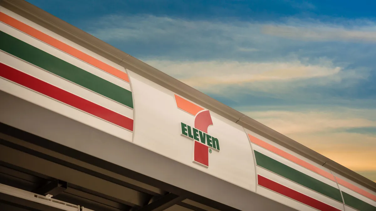 A photo of the sign over the entrance to a store. The sign reads "7-Eleven" in green, red and yellow colors.