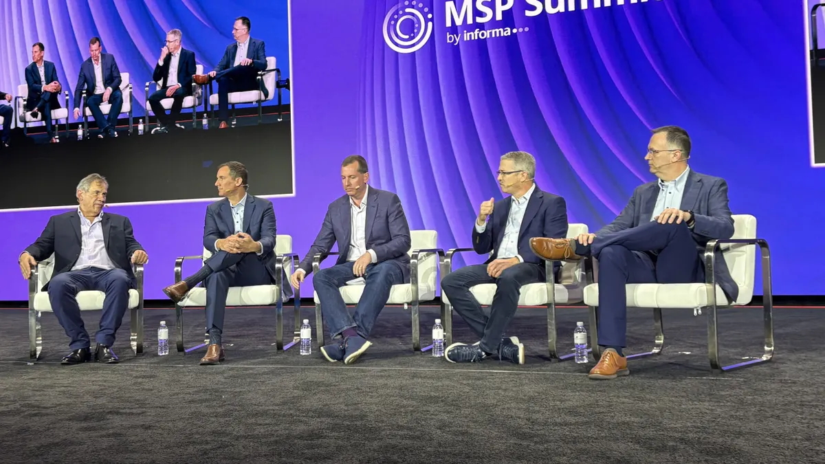 five men sitting on chairs on a keynote stage