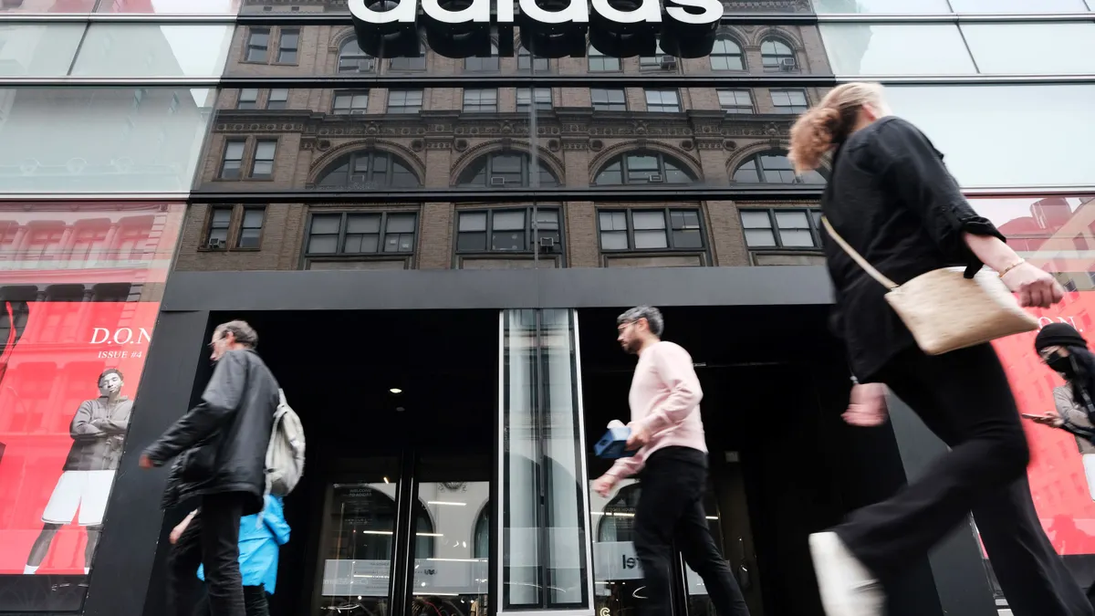 People walk by an Adidas storefront.