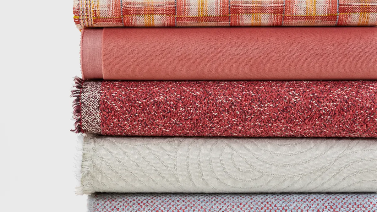 A stack of folded red, white and yellow fabrics with a white background.