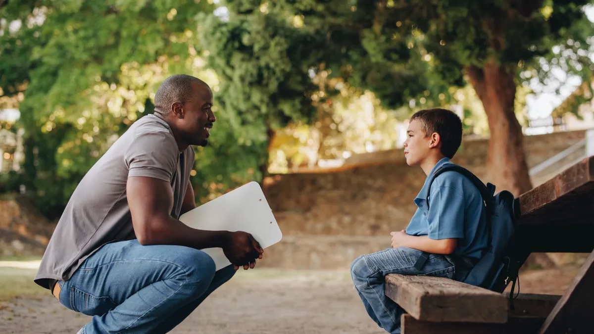 Mentor talking to a young school kid outside class.