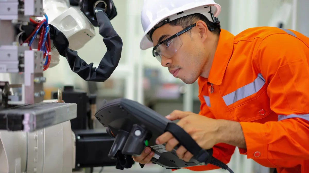 Engineer programming a robot arm in  a factory