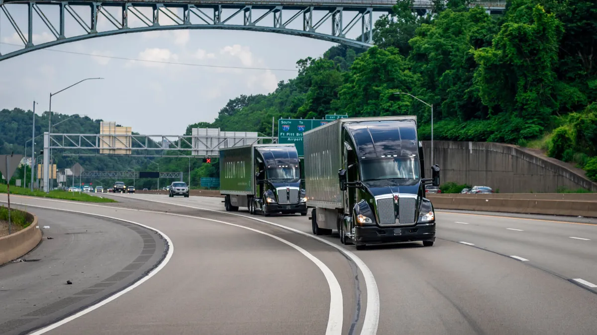 Two Locomation trucks drive on a highway