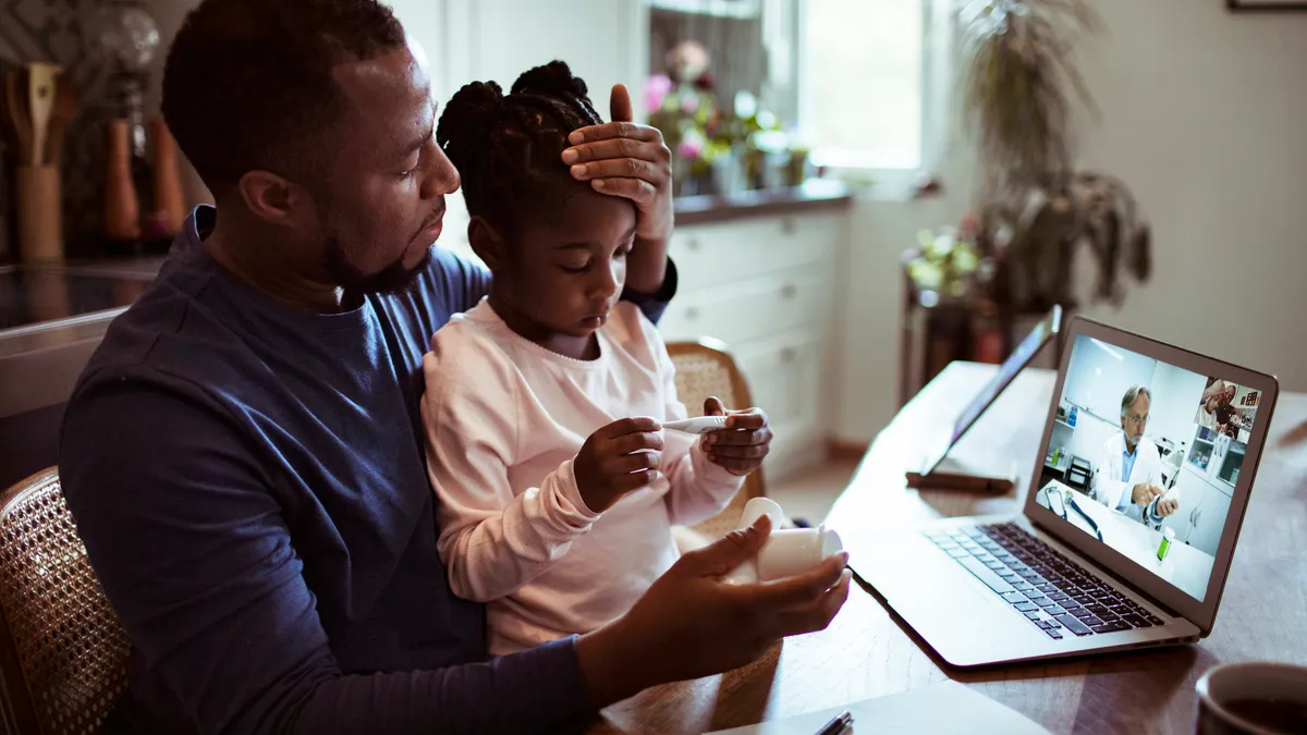 Close up of a father and daughter having a video call with their doctor.