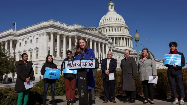 LGBTQ+ advocates holding placards reading "LetKidsPlay" stand in front of Congress