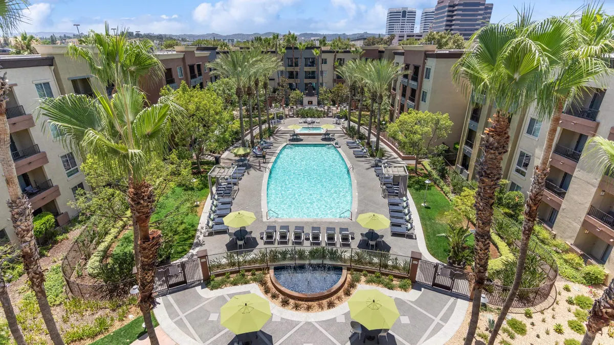 Aerial picture of pool surrounded by palm trees and apartment complex.