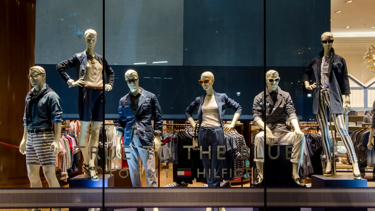 Window display of denim-clad mannequins wearing Tommy Hilfiger clothing.