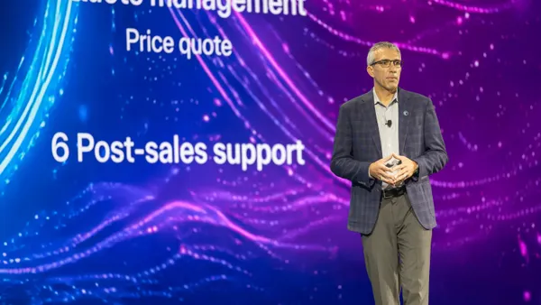 A technology executive stand onstage presenting a conference keynote presentation.