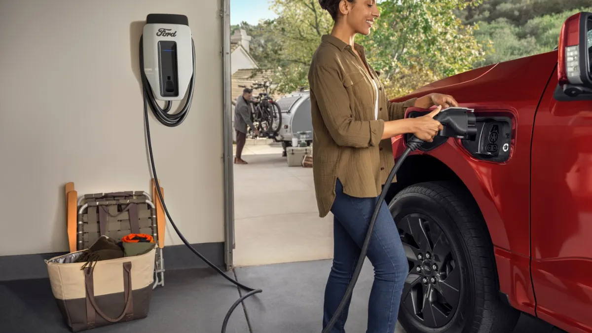 A person plugs an electric F-150 Lighting for charging in a garage.