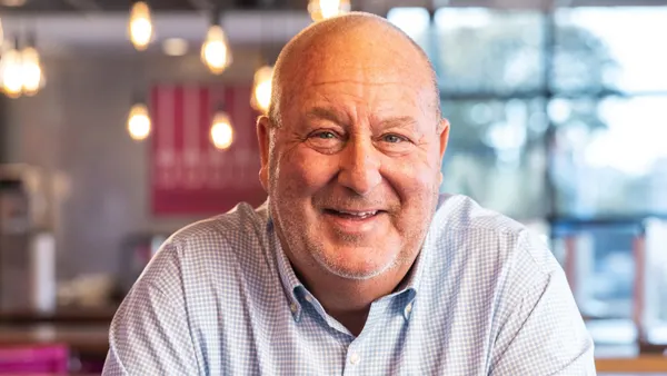 A photograph of a person in a button down shirt smiling at the camera.