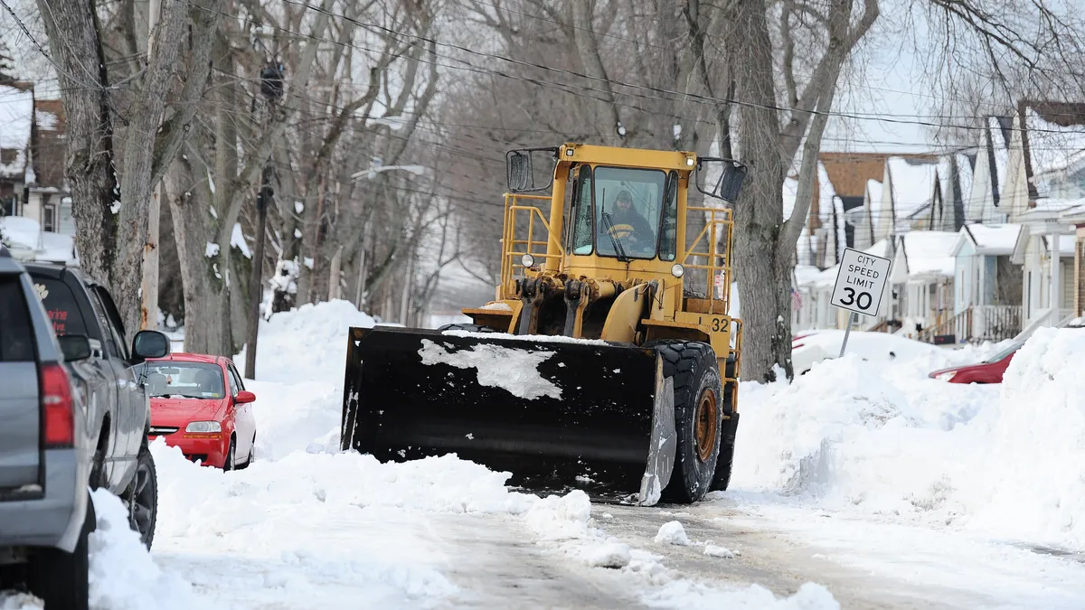 A vehicle with a snow plow on the front on a snow covered street.