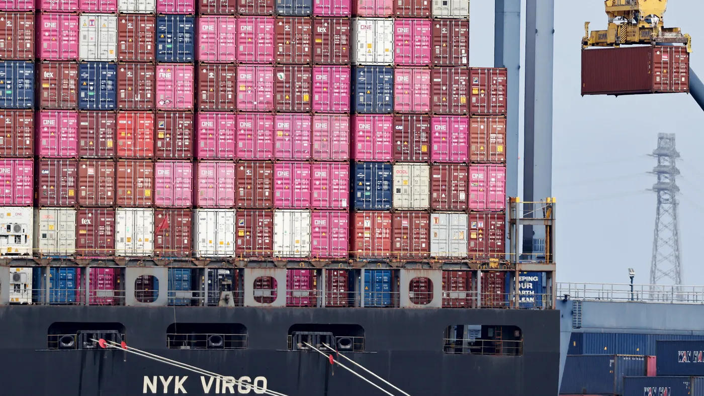Shipping containers of varying colors stacked on a ship.