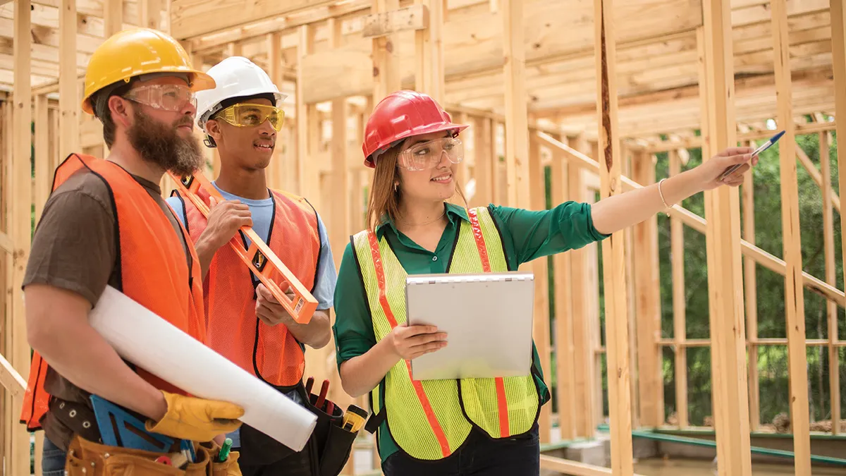 Three people wearing protective construction gear on a construction worksite.