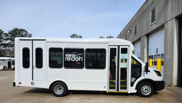 A white van with front and rear doors parked in front of a garage stall.