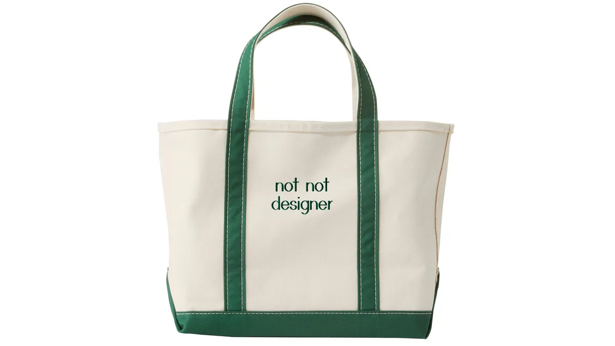 A white canvas tote bag with green handles and green embroidered stitching.