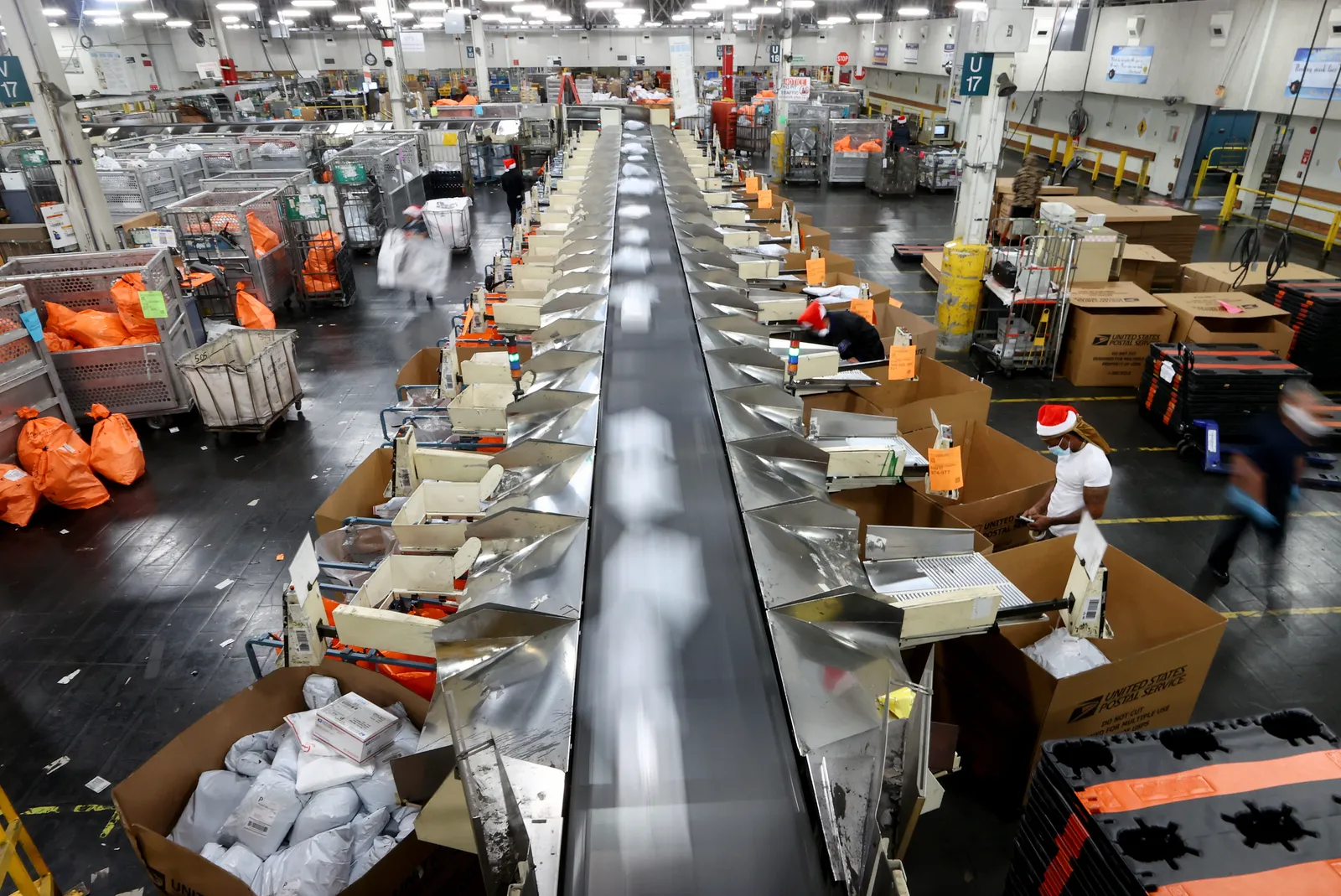 U.S. Postal Service employees work while sorting parcels for distribution inside the Los Angeles Mail Processing & Distribution Center, the largest in the United States, on November 22, 2021.