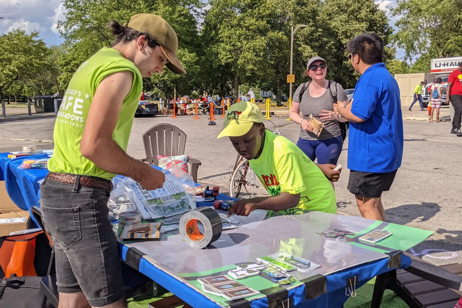 People around a table outdoors on a warm day with stickers and other giveaways.