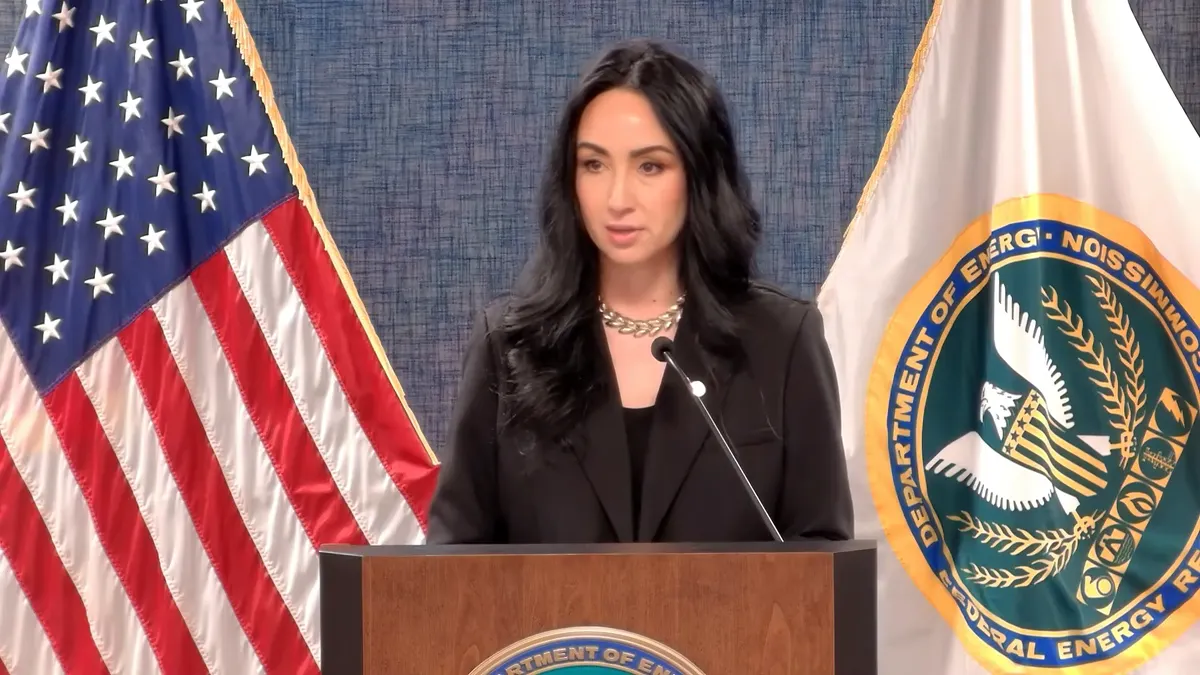 A woman stands in front of two flags.